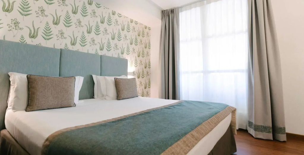 Elegantes Doppelbett mit botanischer Tapete im modernen Hotelzimmer