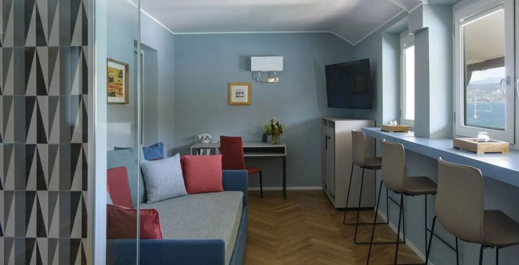 Hellblaues Zimmer mit Sofa und Schreibtisch in der Dei Poeti Suite
