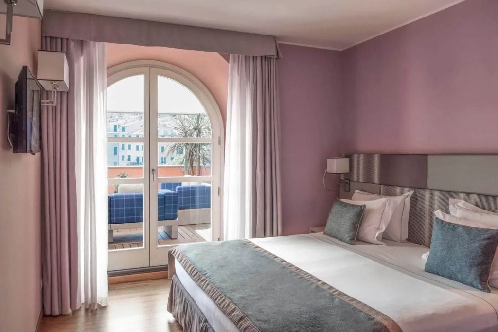 Helles Schlafzimmer mit Doppelbett und Balkon mit Meerblick