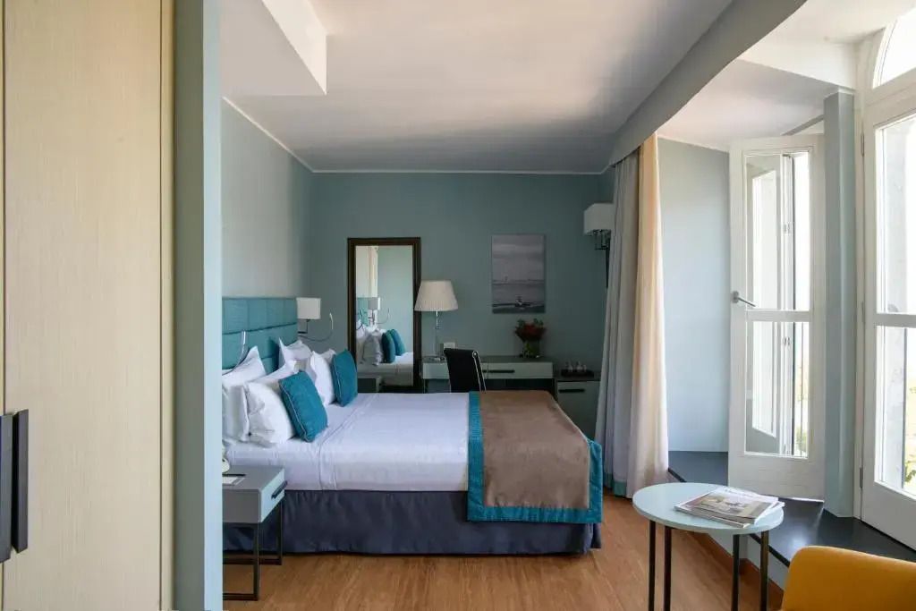 Modernes Deluxe Doppelzimmer mit großem Bett, Schreibtisch und lichtdurchfluteten Fenstern.