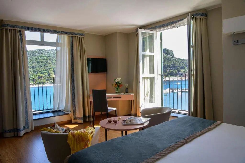 Deluxe Doppelzimmer mit Meerblick von zwei Fenstern, elegantem Interieur und Möbeln.