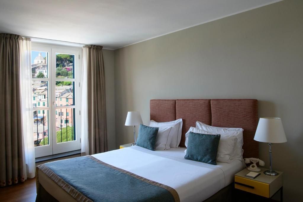 Helles Doppelzimmer mit großem Bett und Fensteraussicht auf die Umgebung.
