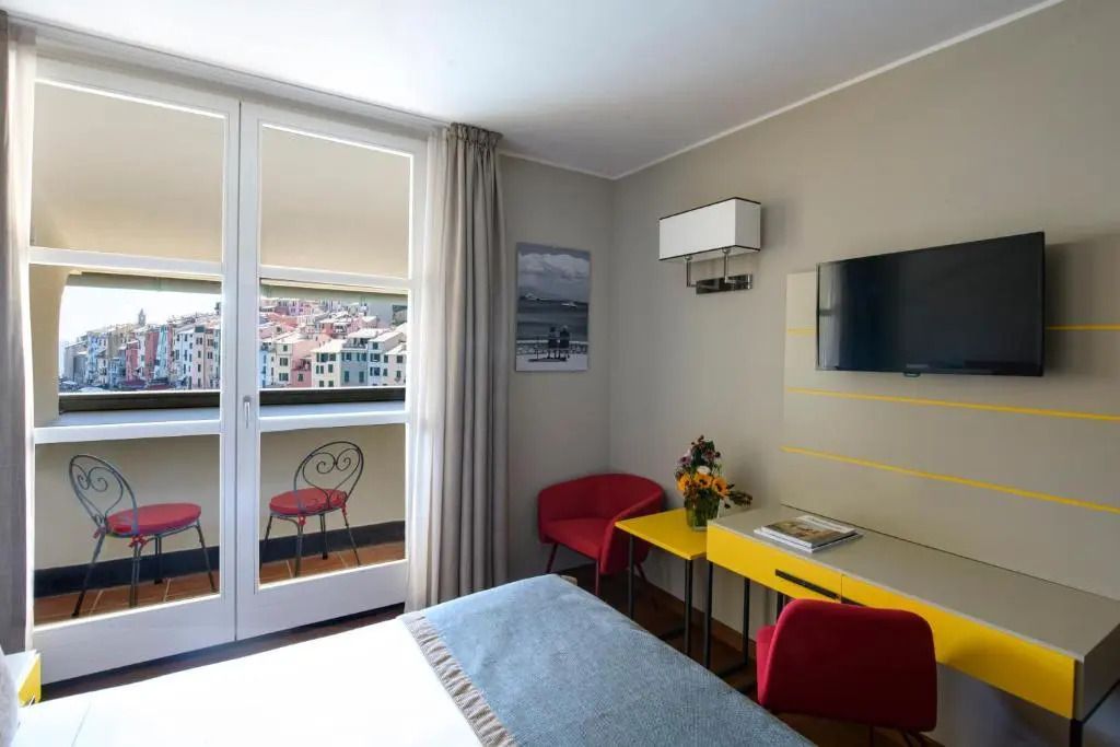 Gemütliches Zimmer mit Fernseher und Zugang zu einem Balkon mit Stadtblick.