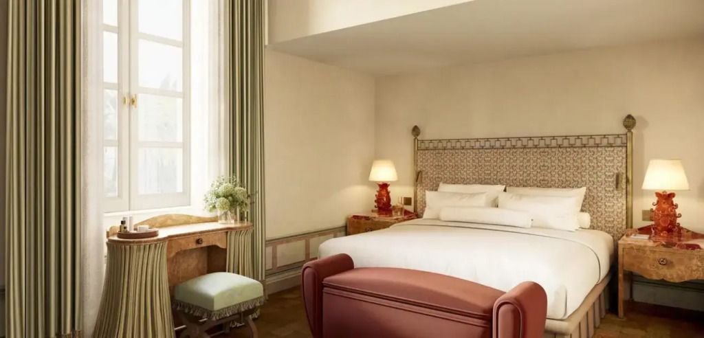 Elegantes Doppelzimmer mit weißem Bett und rotem Fußteil. Helle Einrichtung und Schreibtisch