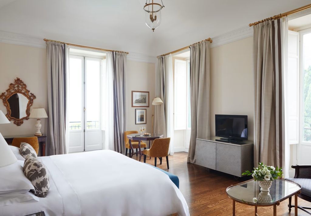 Geräumiges Zimmer mit Doppelbett, eleganten Möbeln und großen Fenstern mit Meeresblick.