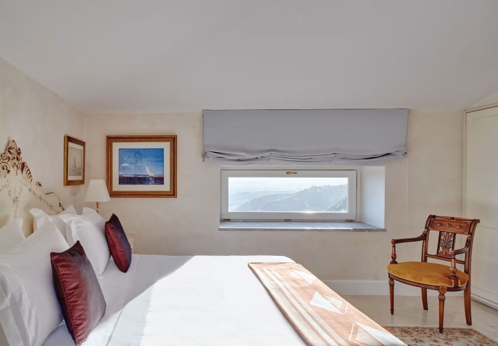 Helles Schlafzimmer mit Aussicht auf die Landschaft und luxuriösen Kissen.