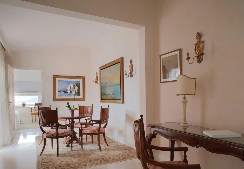 Elegantes Wohnzimmer mit antiken Möbeln und Kunstwerken an den Wänden.