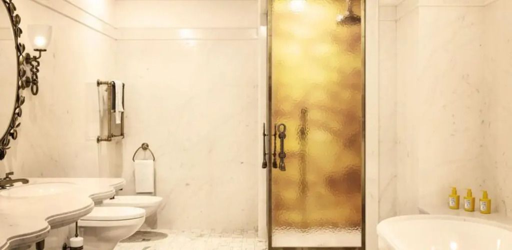 Helles Badezimmer mit großer Dusche und goldenen Akzenten