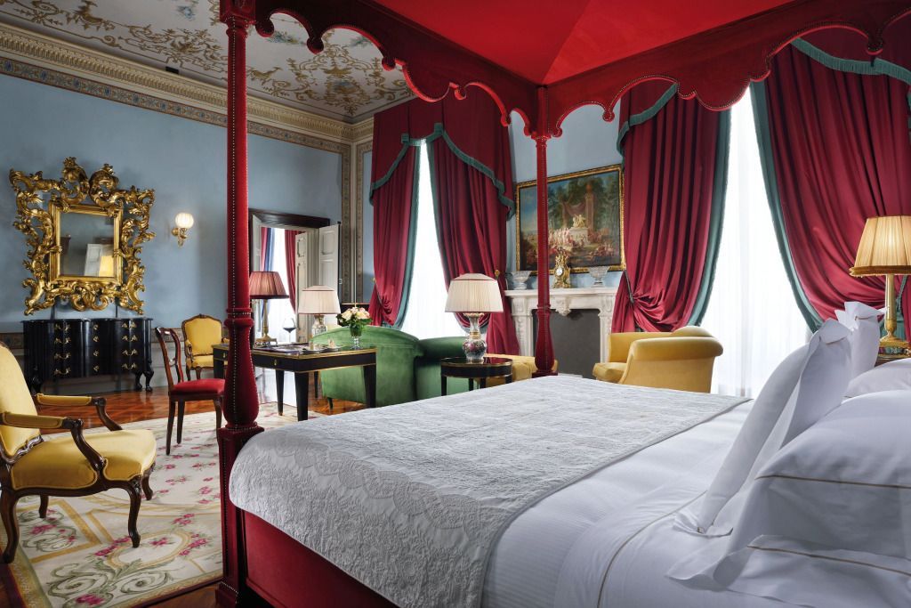 Elegantes Schlafzimmer mit Himmelbett, roten Vorhängen und antiken Möbeln