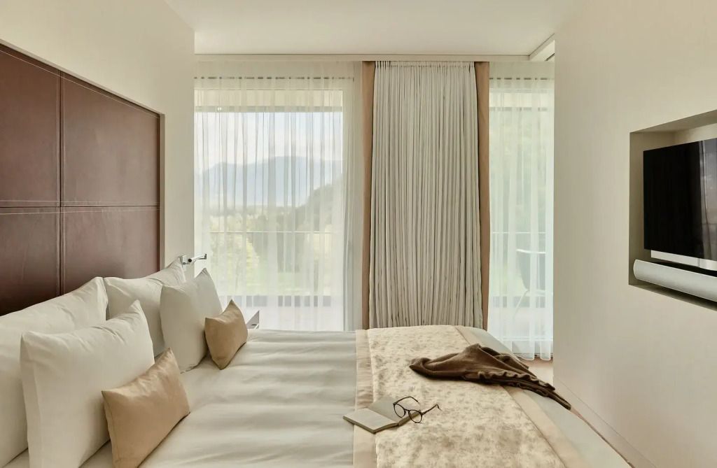 Helles Schlafzimmer mit großen Fenstern und Bergblick im Grand Resort Bad Ragaz
