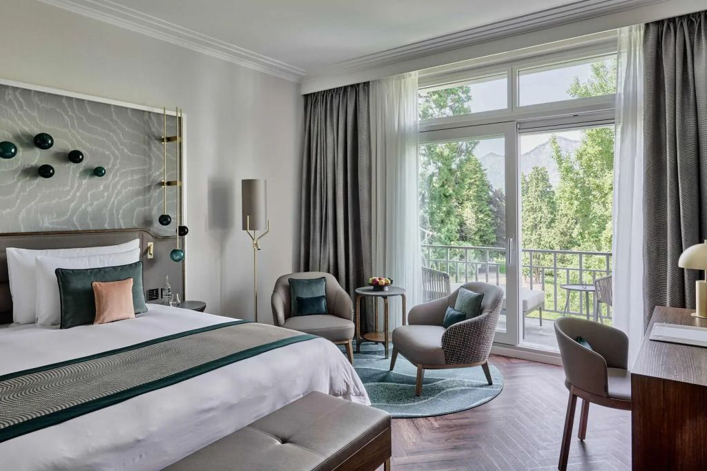Elegantes Doppelzimmer mit großem Fenster, gemütlichen Sesseln und Balkon mit Blick ins Grüne