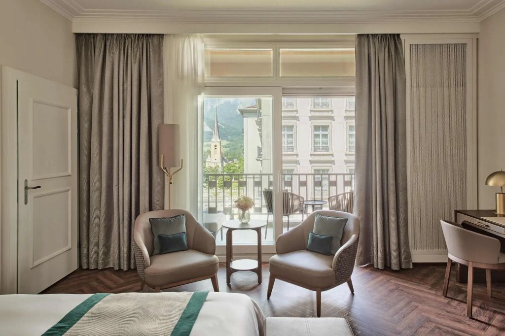 Zimmer mit Balkonblick auf die Stadt und bequemen Sesseln