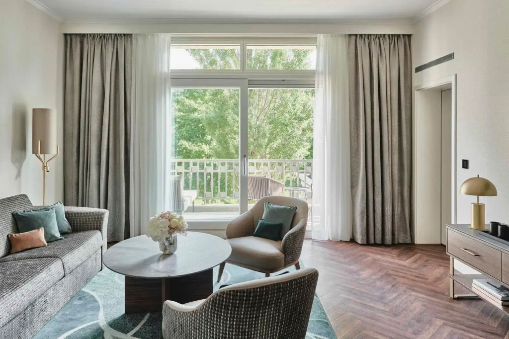 Sitzbereich mit Tisch und Stühlen vor großem Fenster mit Blick auf den Garten