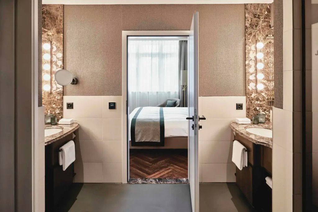 Badezimmer mit zwei Waschbecken und Blick auf das Schlafzimmer der Suite