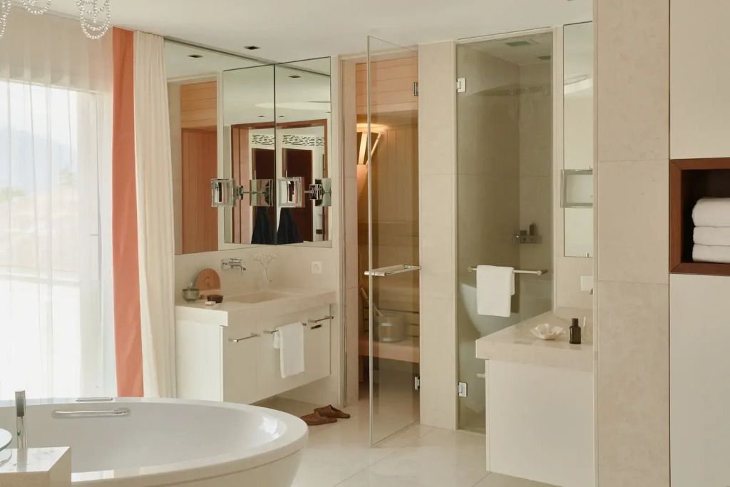 Modernes Badezimmer mit großer Badewanne und Glastür zur Sauna