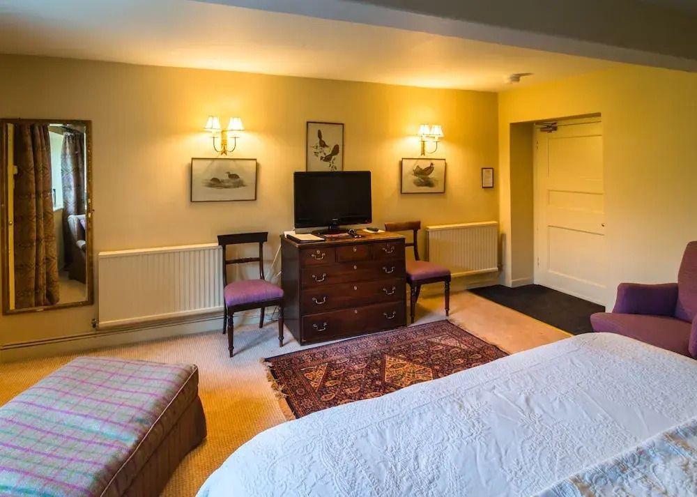 Geräumiges Schlafzimmer mit Teppich, Kommode, Fernseher und stilvollen Wandleuchten