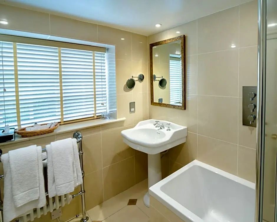 Helles Badezimmer mit rechteckiger Badewanne und großem Spiegel über einem Waschtisch
