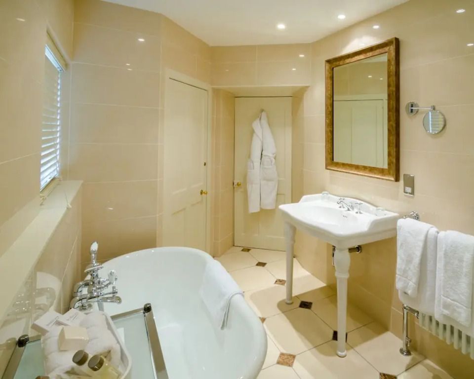 Badezimmer in Beige mit Badewanne, Waschbecken und Wandspiegel