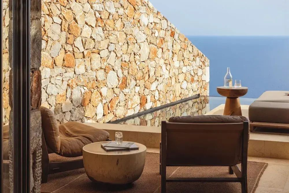 Außenbereich mit Steinwand und Blick aufs Meer von komfortablen Sitzplätzen aus