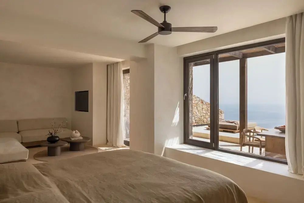 Innenraum einer Suite mit großen Fenstern und einem gemütlichen Bett