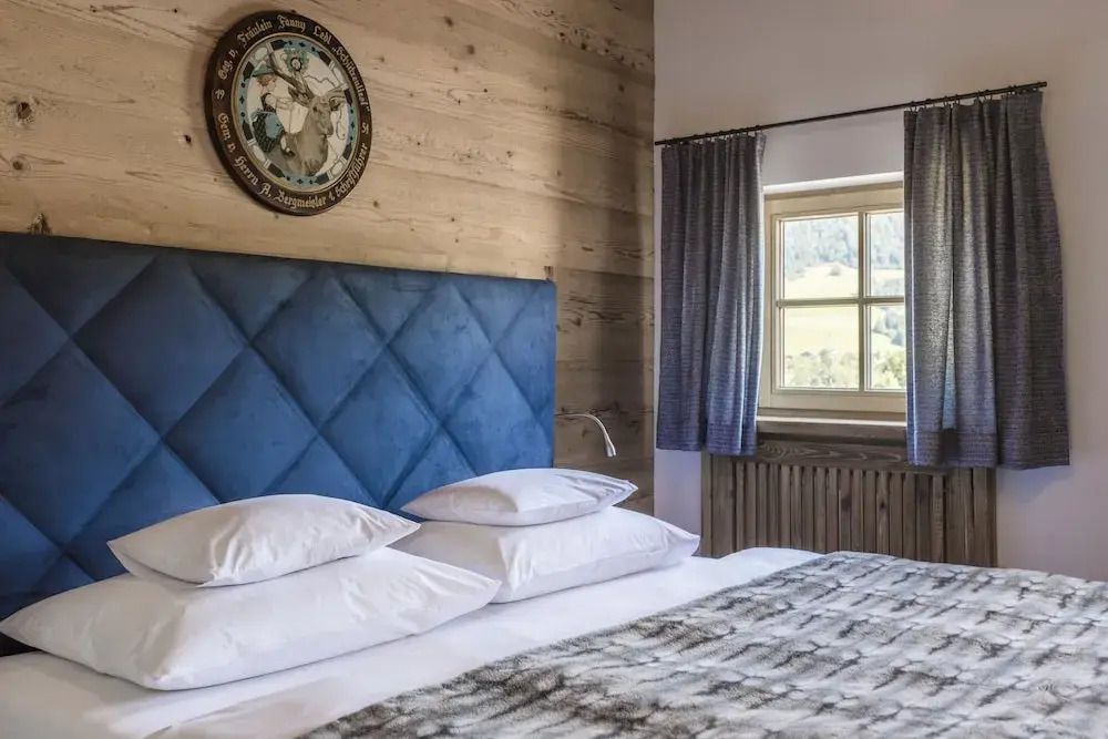 Schlafzimmer mit Holzvertäfelung und blauem Kopfteil