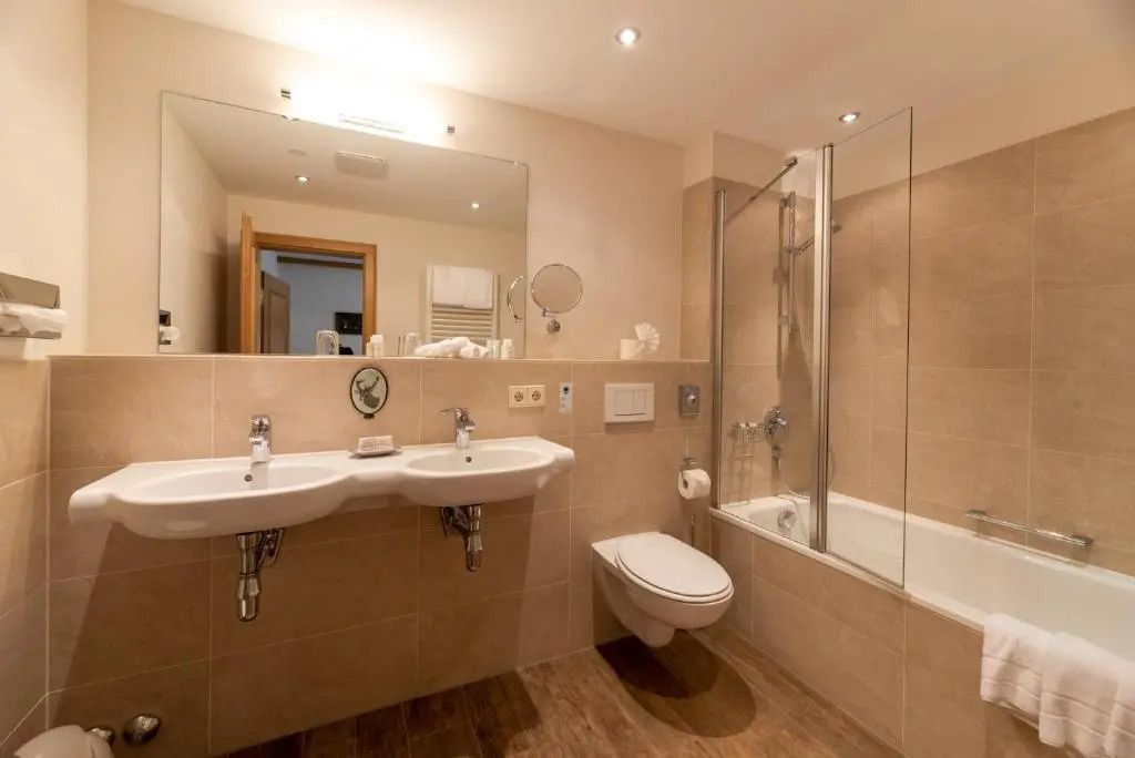 Badezimmer mit zwei Waschbecken und Badewanne mit Duschfunktion