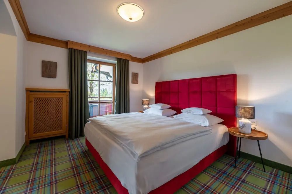 Klassisches Doppelzimmer mit rotem Kopfteil und Fenster mit Ausblick