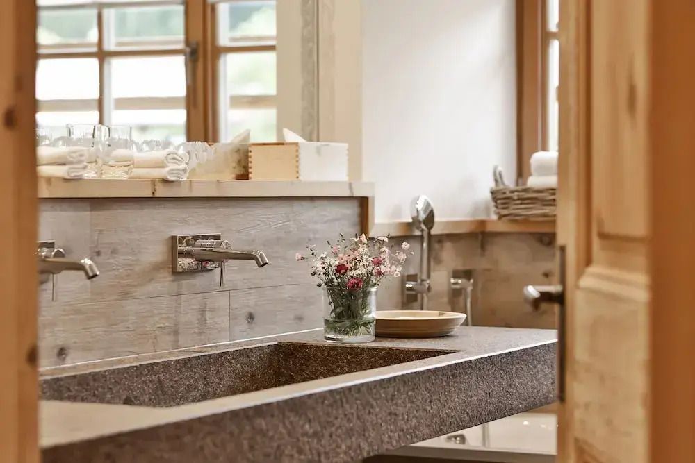 Modernes Badezimmer mit Natursteinwaschbecken und frischen Blumen