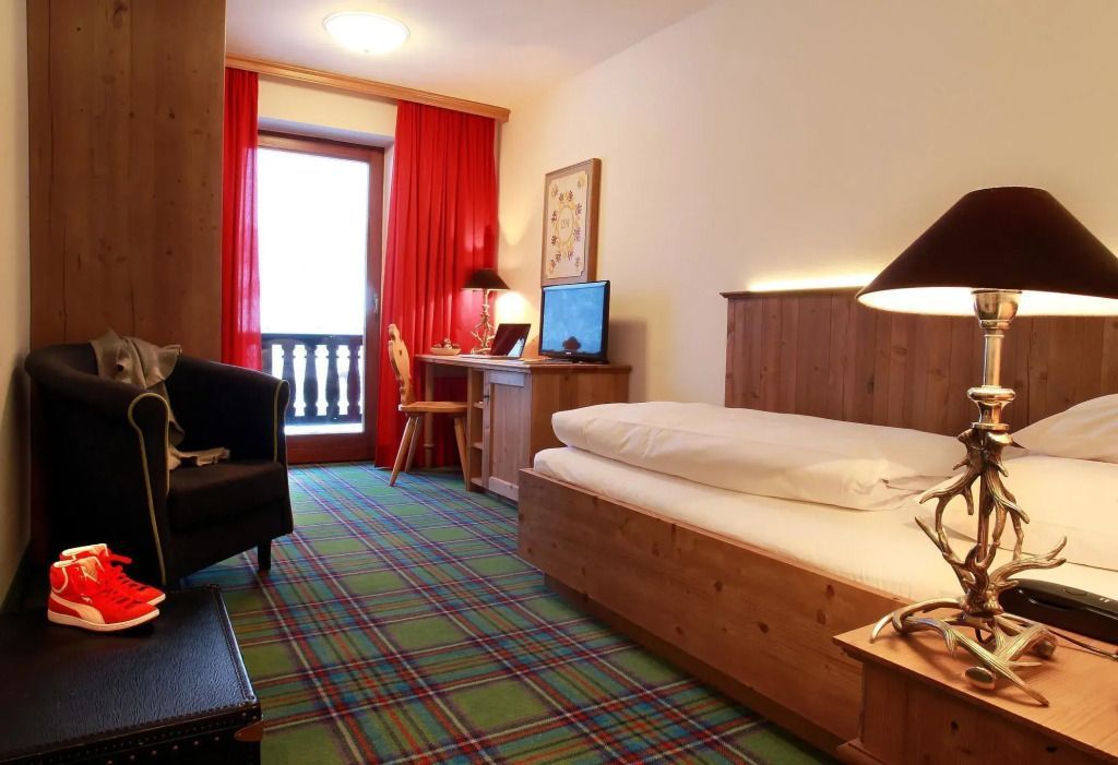 Standardzimmer mit bequemem Bett und Balkon mit rotem Vorhang
