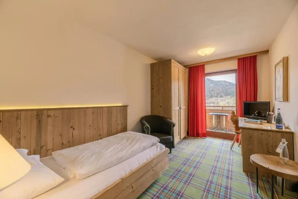 Zimmer mit Holzmöbeln und Aussicht auf einen sonnigen Balkon