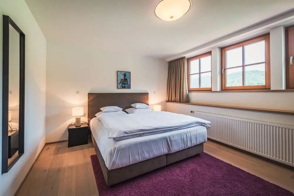 Schlafzimmer mit Doppelbett und zwei Fenstern für viel Tageslicht