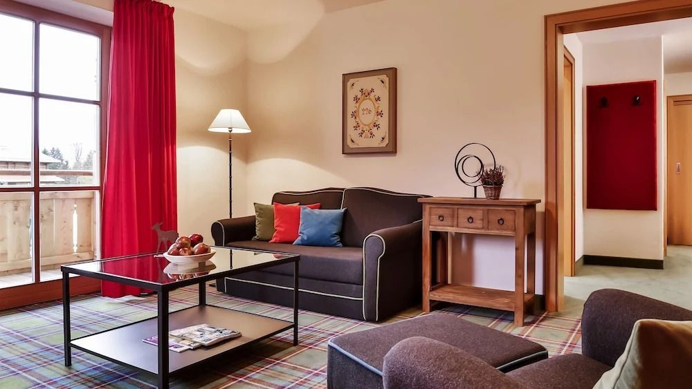 Gemütliches Wohnzimmer mit dunklem Sofa, bunten Kissen und stilvoller Dekoration.