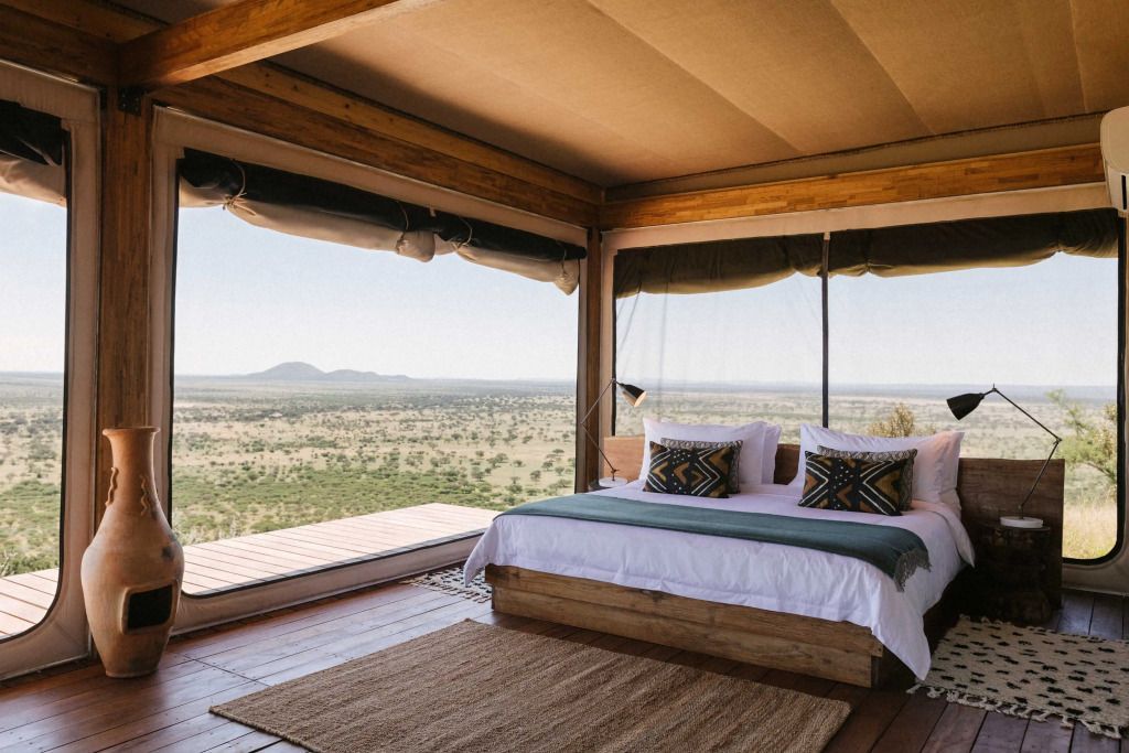 Luxuriöses Zimmer mit großem Bett und Panoramablick über die afrikanische Savanne