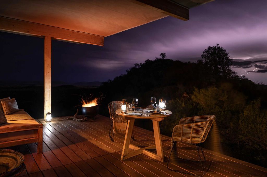 Terrasse mit Tisch und Stühlen im Schein von Laternen unter Nachthimmel