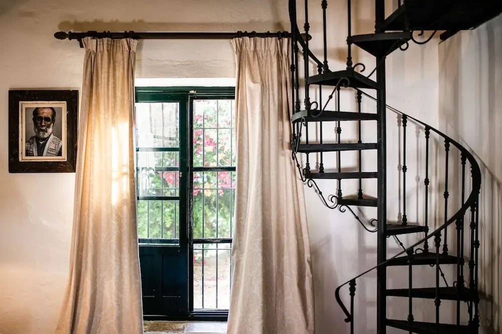 Eisenwendeltreppe neben Fenstertüren mit Vorhängen