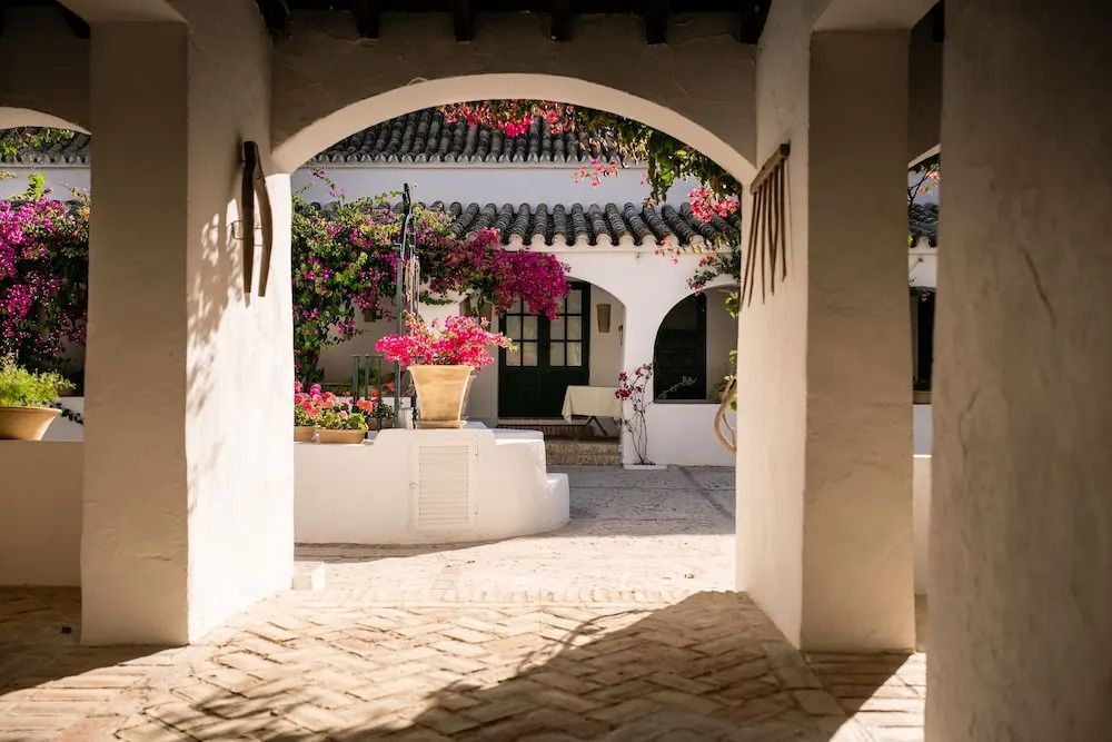 Blick durch einen Bogen auf einen blumenreichen Innenhof