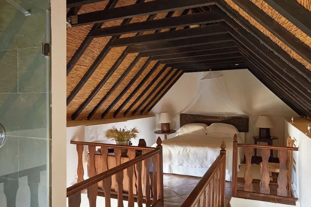 Dachzimmer mit sichtbaren Holzbalken und Doppelbett