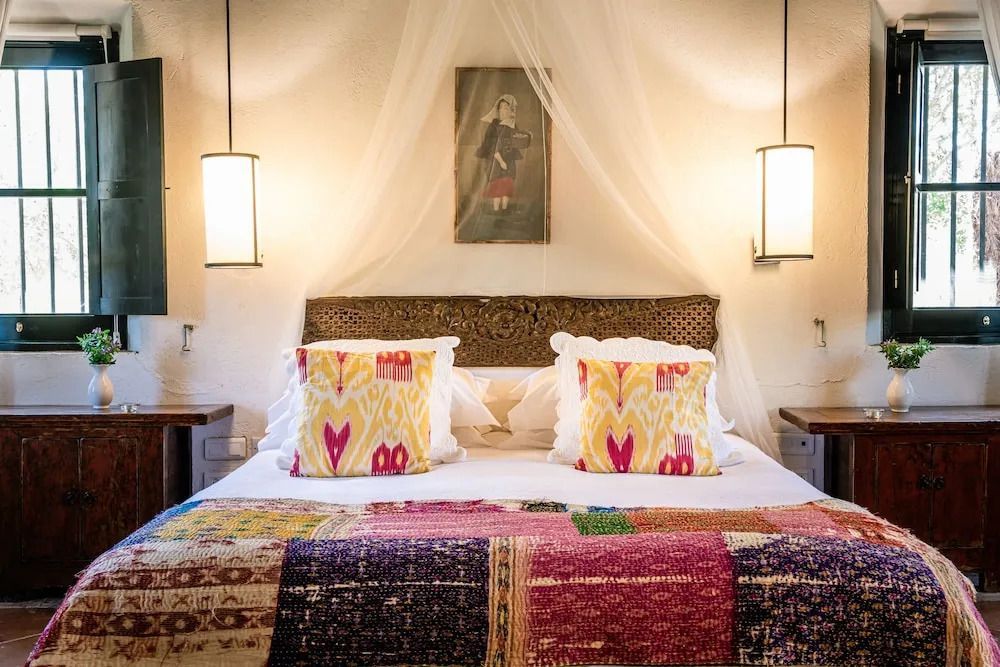 Komfortables Bett in der Suite mit dekorativen Kissen und stilvollem Baldachin