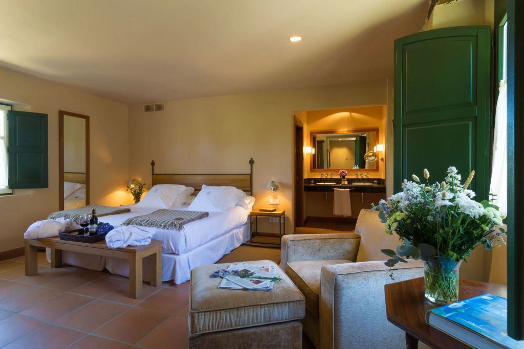 Elegante Suite mit komfortablem Bett, angrenzendem Badezimmer und gemütlichem Sitzbereich