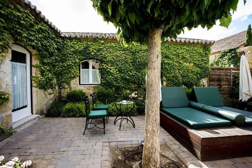 Gartenbereich mit Liegestühlen und Tisch, umgeben von efeubewachsenen Wänden