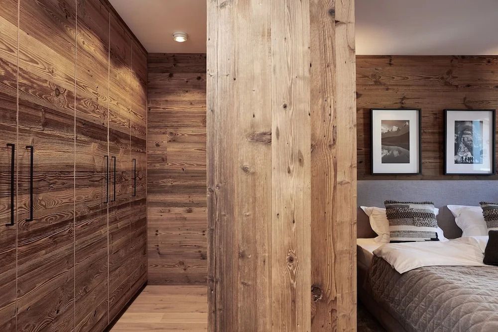 Holzverkleideter Ankleidebereich mit Einbauschrank und Teilansicht eines Bettes