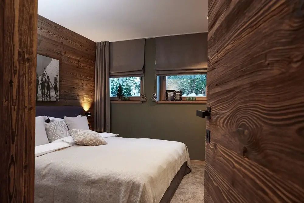 Gemütliches Schlafzimmer mit Holzverkleidung und großen Fenstern