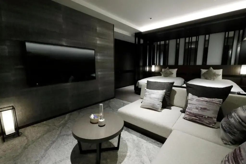 Modernes Hotelzimmer mit zwei Einzelbetten, einem Sofa und einem Fernseher