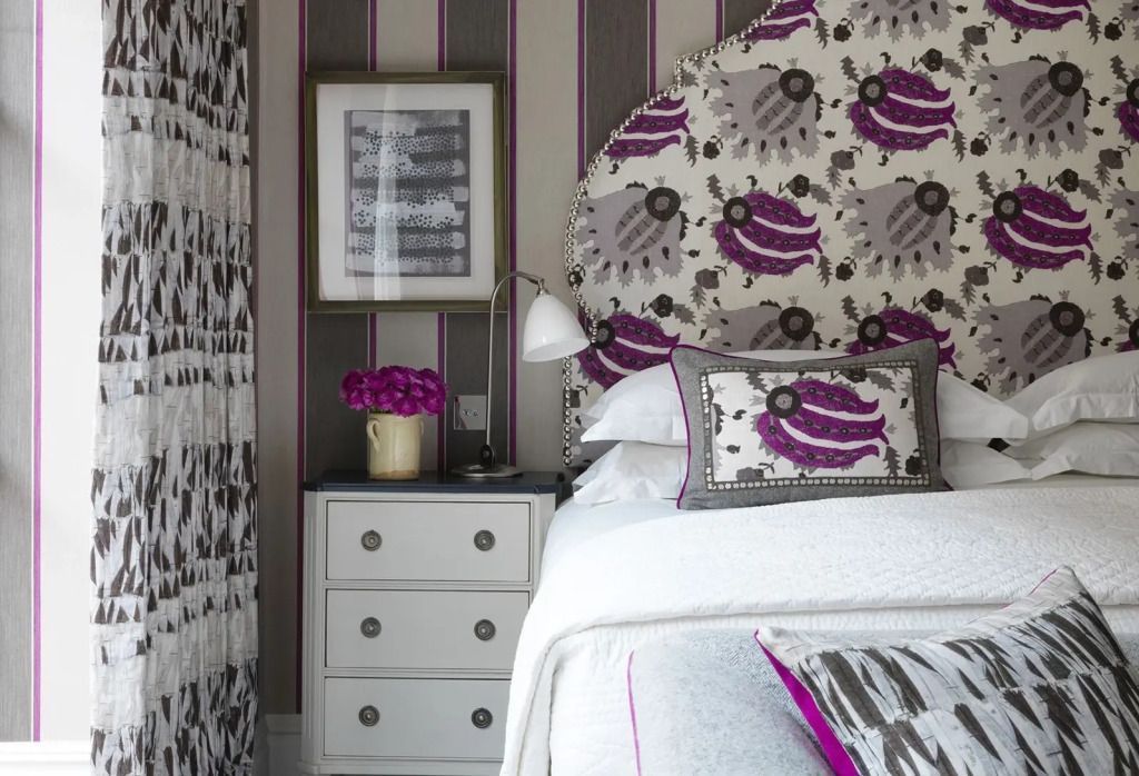 Nachttisch mit Blumen und kunstvollem Kopfteil im Hotelzimmer