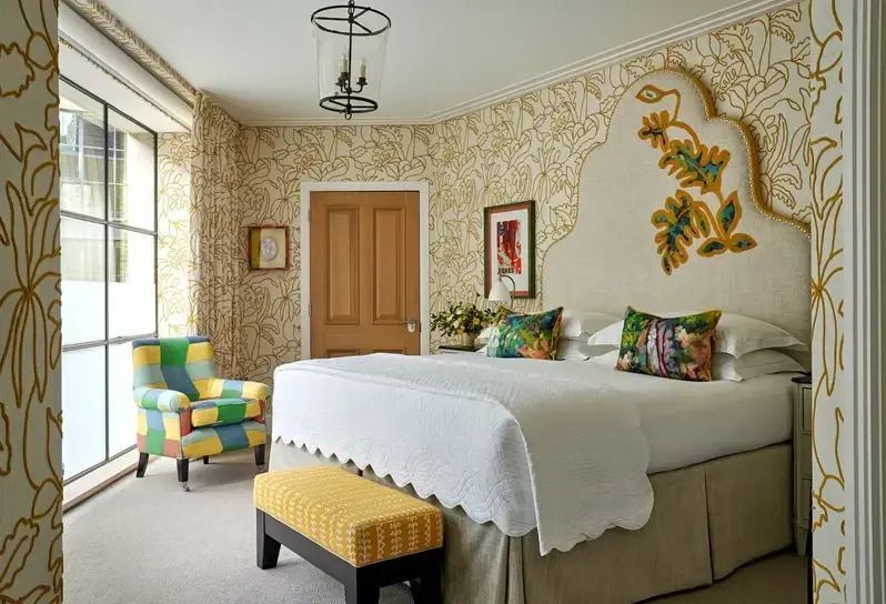 Helles Schlafzimmer mit gelbem Akzentstuhl und kunstvollem Kopfteildesign