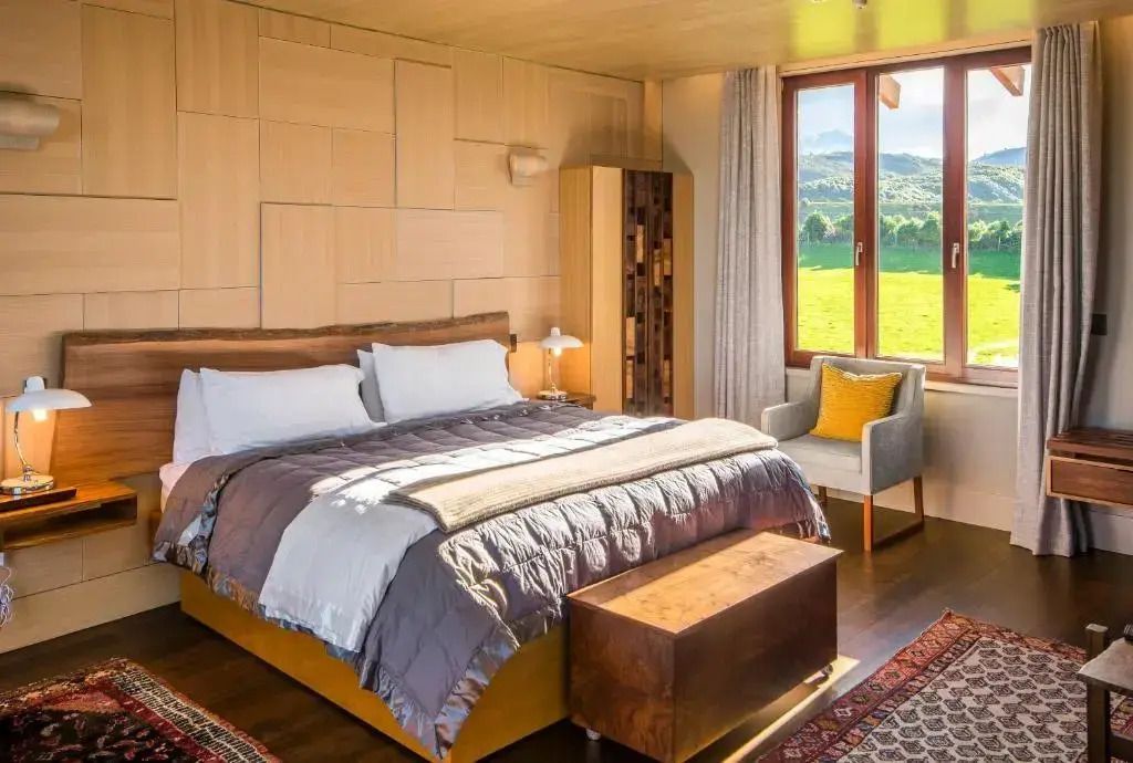 Gemütliches Schlafzimmer mit großem Fenster und Blick auf die grüne Landschaft