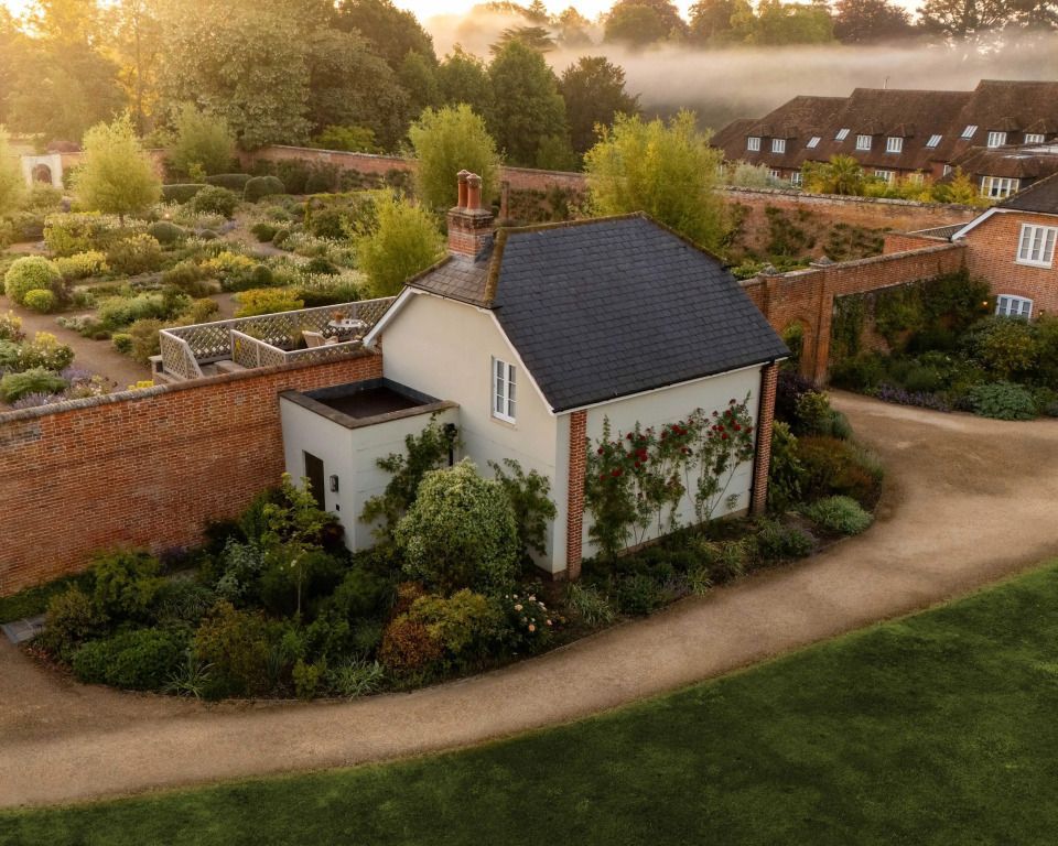 Charmante Hütte mit gepflegtem Garten und umgeben von Ziegelmauer.