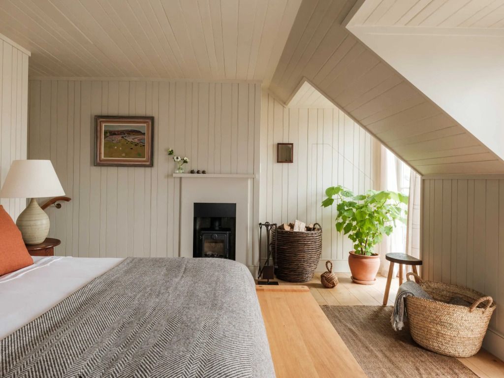 Gemütliches Schlafzimmer mit Kamin, Pflanzen und Holzdekor.