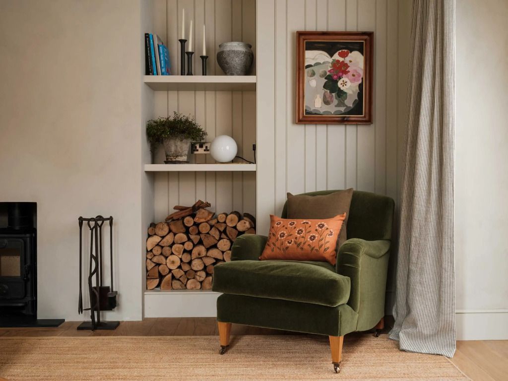 Gemütliche Ecke mit Sessel, Bücherregal und Kaminholz.