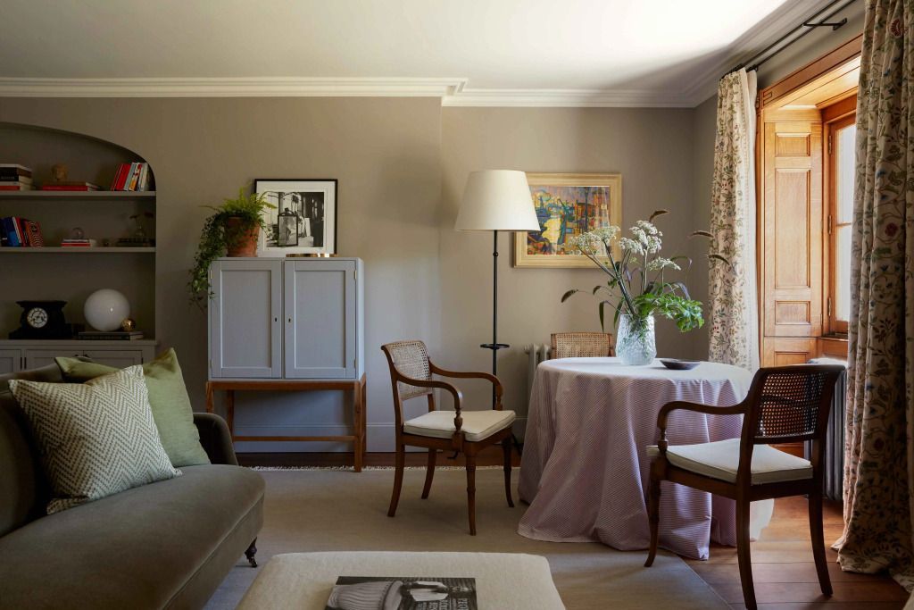 Helles Zimmer mit Tisch und Stühlen sowie dekorativen Kunstwerken an der Wand